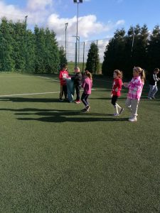 Uczniowie na murawie szkolnego orlika podczas sprzątania świata. W oddaleniu widać dwóch chłopców trzymających worek na śmieci.