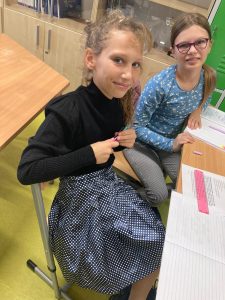 Zdjęcie dwóch uczennic siedzących przy stoliku. Jedna z dziewczyn ma spódnice w kropki.