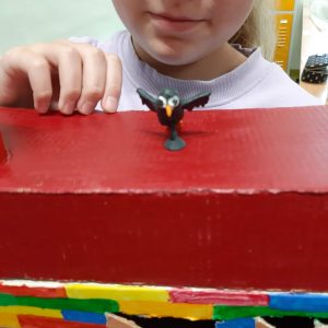 Uczennica trzyma w dłoniach makietę. Na zdjęciu zbliżenie na wykonanego z modeliny czarnego ptaszka.