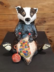 Zdjęcie eksponatu Muzeum Etnograficznego w Toruniu. Na wystawie biało czarny miś robiący na drutach kolorowy kocyk.