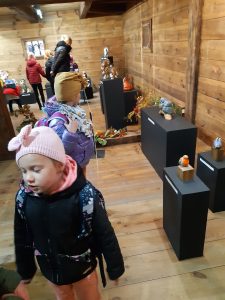 Uczniowie oddziału przedszkolnego podczas zwiedzania wystawy w Muzeum Etnograficznym. Dzieci przyglądają się eksponatom. Dziewczynka na pierwszym planie ma przymknięte oczy i patrzy w drugą stronę.