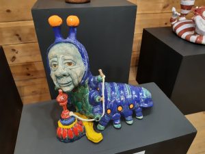 Zdjęcie eksponatu Muzeum Etnograficznego w Toruniu. Na wystawie stonoga z twarzą starca i fajką wodną.