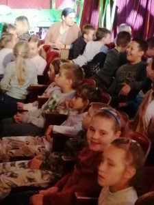 Dzieci klas II i III podczas przedstawienia w Baju Pomorskim w Toruniu. Dzieci siedza obok siebie w fotelikach na widowni.