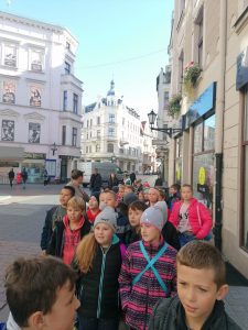 Uczniowie klas II i III podczas spaceru po toruńskiej starówce. Dzieci idą w grupce trzymając się prawej strony ulicy Szerokiej.