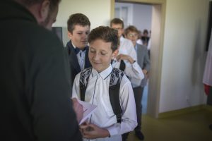 Uczeń czeka na autograf składany przez Łukasza Kazka. Chłopiec ma przymknięte oczy i się uśmiecha. W tle widać kolejkę uczniów czekających na swoją kolej.