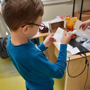 Uczeń klasy czwartej trzyma w dłoniach karteczkę, na której zapisyane jest dla niego zadanie do wykonania.