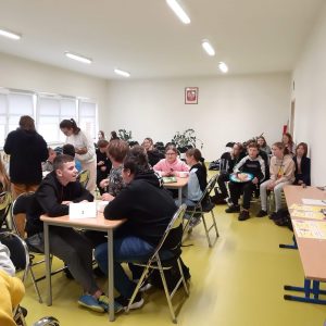 Uczniowie siedzą przy stolikach podczas konkursu wiedzy o Janie Pawle II.