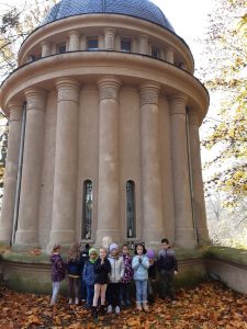 Uczniowie oddziału przedszkolnego stoją w grupie przed okrągłym budynkiem kapliczki.