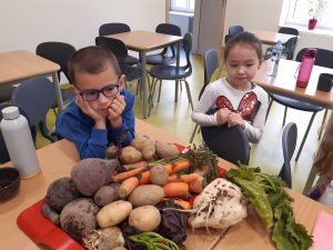 Dwoej uczniów spogląda na ustawione na stoliku szkolnej stołówki warzywa.