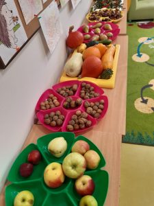 Na stolikach ustawionych w rzędzie leżą na plastikowych taczkach ułożone jabłka, orzechy włoskie, dynie, gruszki i kasztany. Wszystko na osobnych tackach.