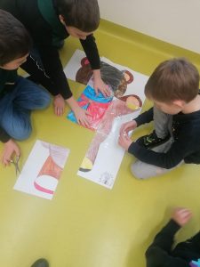 Uczniowie składają puzzle przedstawiające misia na podłodze sali.