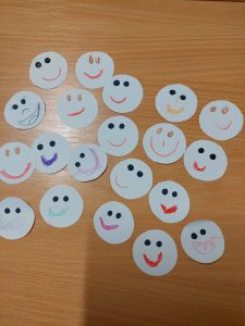 Zdjęcie ułożonych na stoliku białych kółeczek z narysowanymi kolorowymi buźkami.