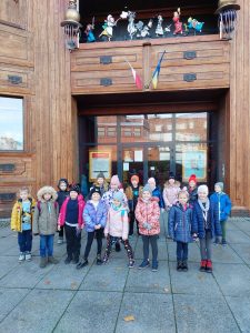 Uczniowie klasy pierwszej pozują do zdjęcia przed wejściem do Baju Pomorskiego. Dzieci ubrane są w kurtki i czapki.