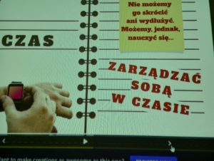 Zdjęcie wyświetlanej prezentacji. Na grafice przypominającej kartkę z zeszytu po lewej stronie napis "CZAS" a pod nim ręka z zegarkiem elektronicznym a po prawej na żółtym tle czerwony napis: "Nie możemy go skrócić ani wydłużyć. Możemy, jednak, nauczyć się...". Pod spodem większy czerwony napis umieszczony lekko pod skosem na liniach zeszytu: ZARZĄĆ SOBĄ W CZASIE.
