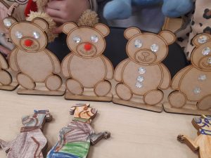 Zdjęcie modeli misi wykonane przez dzieci z oddziału przedszkolnego. Część modeli ozdobionych kryształkami stoi na stoliku, inne leżą przed nimi pokolorowane na brązowo przez dzieci.