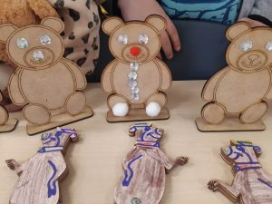 Zdjęcie modeli misi wykonane przez dzieci z oddziału przedszkolnego. Część modeli ozdobionych kryształkami stoi na stoliku, inne leżą przed nimi pokolorowane na brązowo przez dzieci.