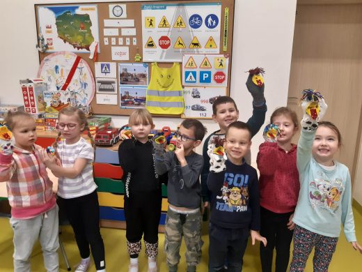 Uczniowie oddziału przedszkolnego pozują do wspólnego zdjęcia w swojej sali. Dzieci na rękach mają założone skarpetkowe pacynki, które sami wykonali.