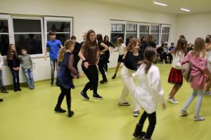 Uczniowie tańczą na sali teatralnej. Zdjęcie wykonane podczas zabawy andrzejkowej.