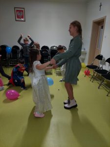 Starsza uczennica tańczy z młodszą uczennicą w stroju księżniczki.