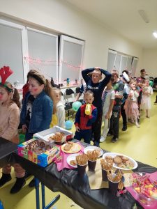 uczniowie stoją w kolejce do stolika ze słodkościami.