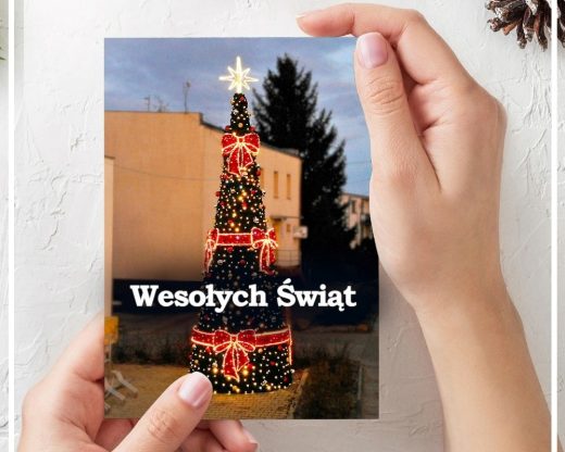 Zdjęcie rąk obejmujących przykładową kartkę świąteczną przygotowaną ze zdjęcia choinki stojącej przed urzędem Gminy Łysomice. Po środku biały napis "Wesołych Świąt".