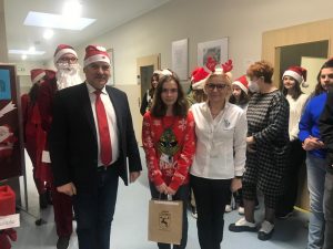 Pan wójt i Pani dyrektor pozują do wspólnego zdjęcia z uczennicą, która otrzymała nagrodę w konkursie plastycznym. W tle stoi święty mikołaj i inni uczniowie.