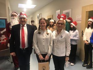 Pan wójt i Pani dyrektor pozują do wspólnego zdjęcia z uczennicą, która otrzymała nagrodę w konkursie plastycznym. W tle widać innych uczniów.