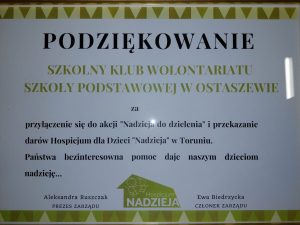 Podziękowania - na białym tle ozdobionym zieloną ramką tekst"PODZIĘKOWANIE SZKOLNY KLUB WOLONTARIATU SZKOŁY PODSTAWOWEJ W OSTASZEWIE za przyłączenie się do akcji "Nadzieja do dzielenia" i przekazanie darów Hospicjum dla Dzieci "Nadzieja" w Toruniu. Państwa bezinteresowna pomoc daje naszym dzieciom nadzieję..." . U dołu logo hospicjum nadzieja oraz nadruk "Aleksandra Ruszczak PREZES ZARZĄDU Ewa Biedrzycka CZŁONEK ZARZĄDU".