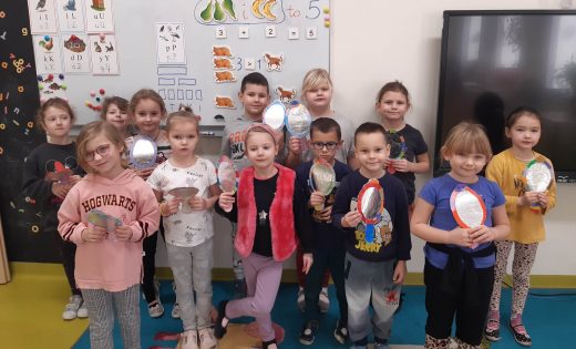 Uczniowie oddziału przedszkolnego pozują do wspólnego zdjęcia trzymając w dłoniach wykonane przez siebie lusterka.