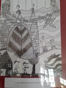 Zdjęcie wyróżnionej pracy plastycznej. Praca wykonana ołówkiem przedstawia sceny z życia księdza Frelichowskiego. Pod praca na białej karteczce nadruk: "Karol Cebulski Szkoła Podstawowa w Ostaszewie".