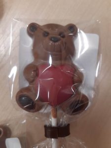 Zdjęcie czekoladowego lizaka w kształcie misia trzymającego czerwone serce. Prezent dla uczniów oddziału przedszkolnego z okazji walentynek.