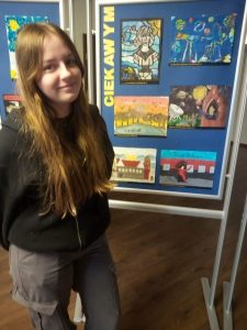 Wyróżniona w konkursie uczennica Zofia Makowska pozuje do zdjęcia na tle galerii stworzonej z nagrodzonych prac plastycznych.