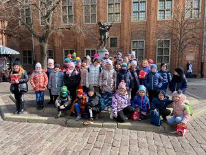 Uczniowie pozują do wspólnego zdjęcia przy pomniku Flisaka na toruńskiej starówce.