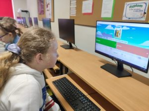 Uczennica klasy czwartej siedzi przy stanowisku komputerowym. Z uwagą wpatruje się w ekran na którym widzi pytanie z quizu.