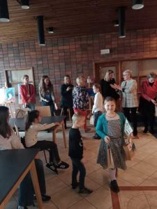 Uczennica Łucja Markowska idzie z odebranymi nagrodami. Dziewczynka uśmiecha się. W tle widać inne osoby. Zdjęcie niewyraźne.