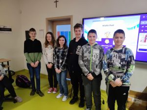 Uczniowie klasy siódmej biorący udział w konkursie pozują do wspólnego zdjęcia na tle tablicy z grafiką i napisem "Wielki Post".