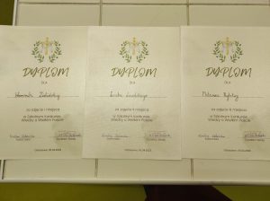 Zdjęcie dyplomów przygotowanych dla zwycięzców w konkursie. Trzy dyplomu ułożono obok siebie na białym stole. Każdy z nich ozdobiony jest grafiką z krzyżem pod którym umieszczono napis "Dyplom dla" pod nim wypisane są ręcznie nazwiska zwycięzców - od lewej strony "Weroniki Zielińskiej", "Leszka Lewalskiego", "Mateusza Rybitwy". Pod nazwiskami zamieszczono odpowiednio napisy " za zajęcie I miejsca w Szkolnym Konkursie Wiedzy o Wielkim Poście", " za zajęcie II miejsca w Szkolnym Konkursie Wiedzy o Wielkim Poście" i " za zajęcie III miejsca w Szkolnym Konkursie Wiedzy o Wielkim Poście". Poniżej umieszczone zostały podpisy nauczycielki religii oraz Pani Dyrektor w raz z pieczątką szkoły.