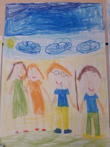 Zdjęcie rysunku wykonanego przez ucznia oddziału przedszkolnego kredkami. Rysunek przedstawia cztery postacie a nad nimi niebo i słońce.