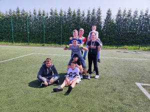 Chłopcy z klasy szóstej pozują do wspólnego zdjęcia na boisku. Sześciu chłopców ustawiło się w rzędzie. Dwóch z przodu siedzi a kolejni stoją. Obok dwóch chłopców stoi i jeszcze jeden siedzi po drugiej stronie.