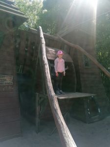 Dziewczynka stoi na podeście drewnianego budynku.