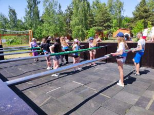 Uczniowie stoją w kilku rzędach przy długich prętach. Czekają na rozpoczęcie gry w piłkarzyki.