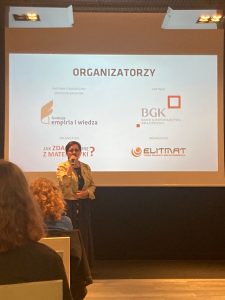 Pani wicekurator podczas przemowy na spotkaniu. W tle na rzutniku wyświetleni są organizatorzy i sponsorzy projektów matma^2 i matura+.