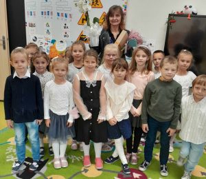 Uczniowie oddziału przedszkolnego pozują do wspólnego zdjęcia z wychowawczynią. Pani trzyma w dłoniach otrzymane upominki.