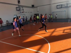 Uczniowie biegną przez salę gimnastyczna podnosząc wysoko w górę kolana. Zdjęcie wykonane w ruchu.