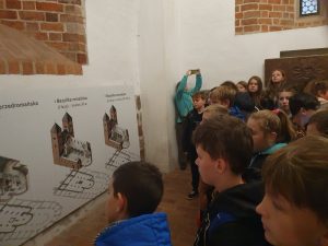 Uczniowie stoją przed makietą przedstawiającą wygląd gnieźnieńskiej katedry na poszczególnych etapach.