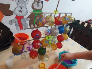 Zdjęcie stojaka z zawieszonymi na nim, wykonanymi przez uczniów bombkami.