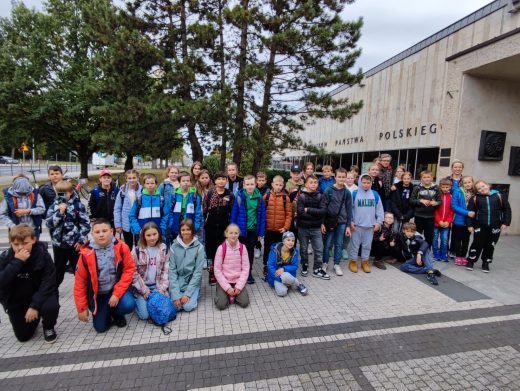 Uczniowie pozują do wspólnego zdjęcia przed budynkiem muzeum powstania państwa polskiego.