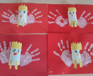 Zdjęcie czterech prac plastycznych przypominających godło Polski. Na czerwonym tle przyklejona jest rolka papieru ozdobiona koroną. Obok niej odciśnięte są białe dłonie. Prace ułożone są po dwie obok siebie, w dwóch rzędach.