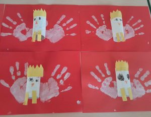 Zdjęcie czterech prac plastycznych przypominających godło Polski. Na czerwonym tle przyklejona jest rolka papieru ozdobiona koroną. Obok niej odciśnięte są białe dłonie. Prace ułożone są po dwie obok siebie, w dwóch rzędach.