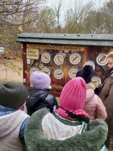 Uczniowie stoją przed tablicą prezentującą ptaki występujące na Barbarce.